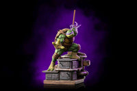 Iron Studios 1/10 Donatello statue in a dynamic pose, wielding a bo staff atop a detailed industrial sewer base.