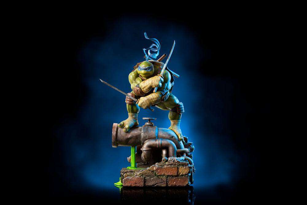 Iron Studios 1/10 Leonardo statue in a dynamic pose with dual katanas, standing on a detailed sewer pipe base.