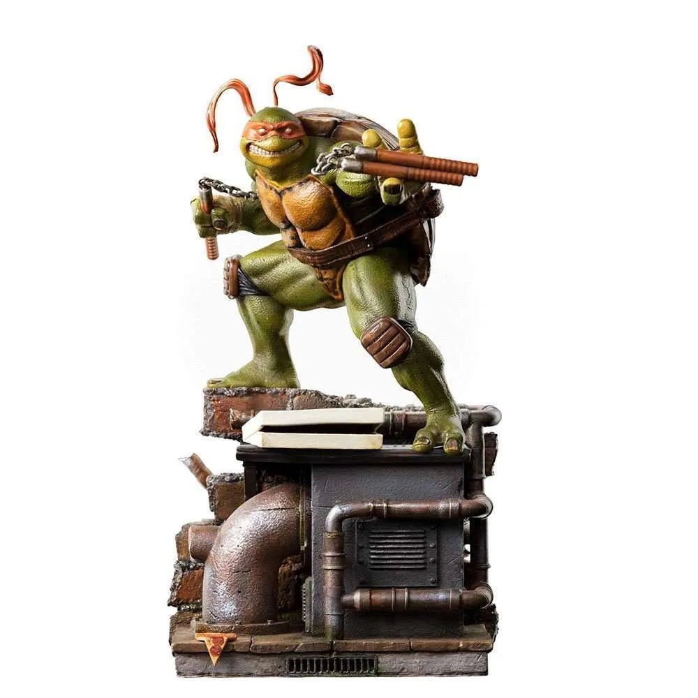 Iron Studios 1/10 Michelangelo statue in a dynamic pose with nunchucks, standing on a detailed sewer-themed base.