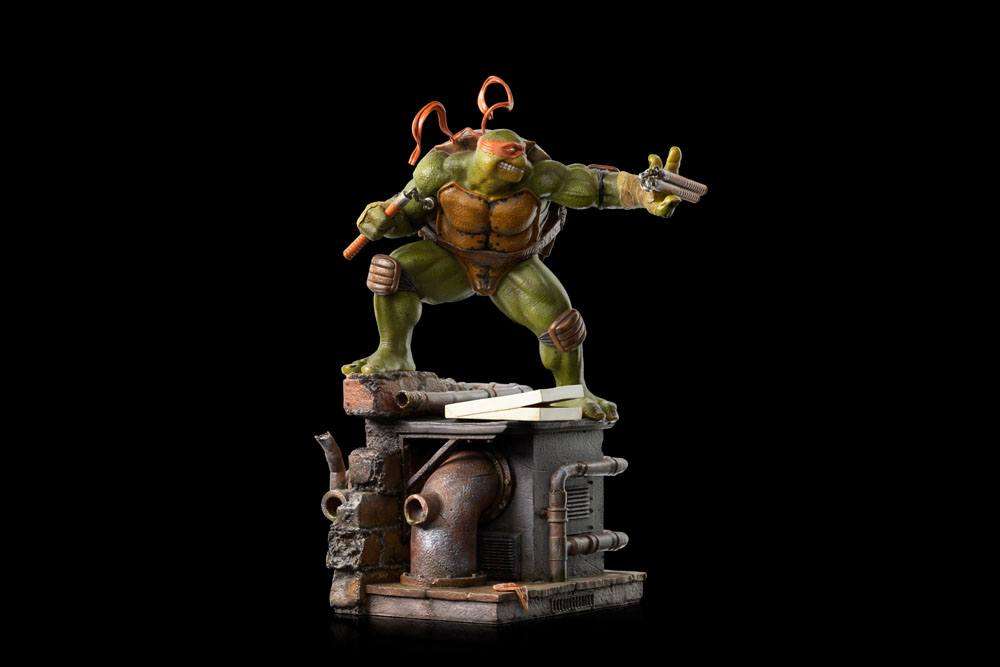 Iron Studios Michelangelo 1/10 scale statue in a dynamic pose on a detailed sewer base against a black background.