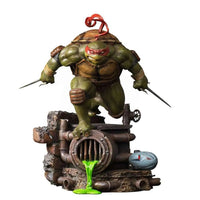 Iron Studios 1/10 Raphael statue in a dynamic pose with twin sai, standing on a sewer base with green ooze.