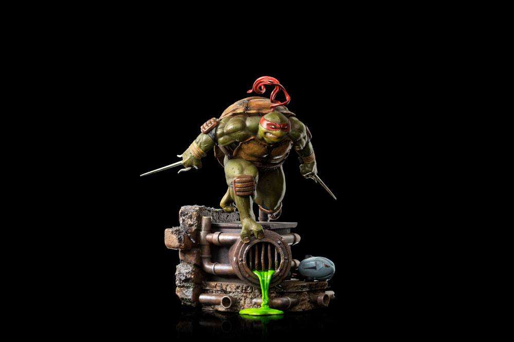Iron Studios 1/10 Raphael statue in a dynamic pose, wielding twin sai on a sewer-themed base with green slime.