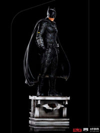 Iron Studios 1/10 scale The Batman statue in a side view, featuring a detailed black tactical suit and cape on a base.