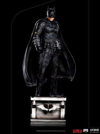 Iron Studios 1/10 scale The Batman statue in a black tactical suit standing on a detailed base against a black background.