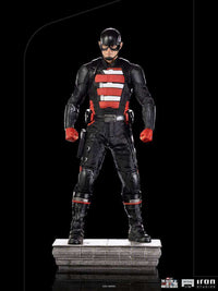 Iron Studios 1/10 John Walker U.S. Agent statue in a black tactical suit with red accents, standing on a stone base.