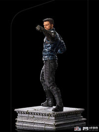 Side view of Iron Studios Bucky Barnes 1/10 scale statue in a blue jacket and black pants on a stone-textured base.