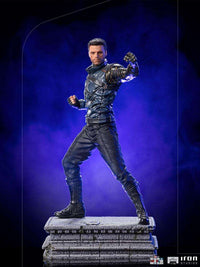 Iron Studios Bucky Barnes 1/10 scale statue in a dynamic combat pose on a stone base against a purple background.