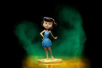 Iron Studios 14 cm Betty Rubble Art Scale statue in a blue dress standing on a stone base against a green background.