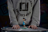 Iron Studios 1/10 scale Betty Rubble statue in a blue dress, standing on a round base in front of a person.