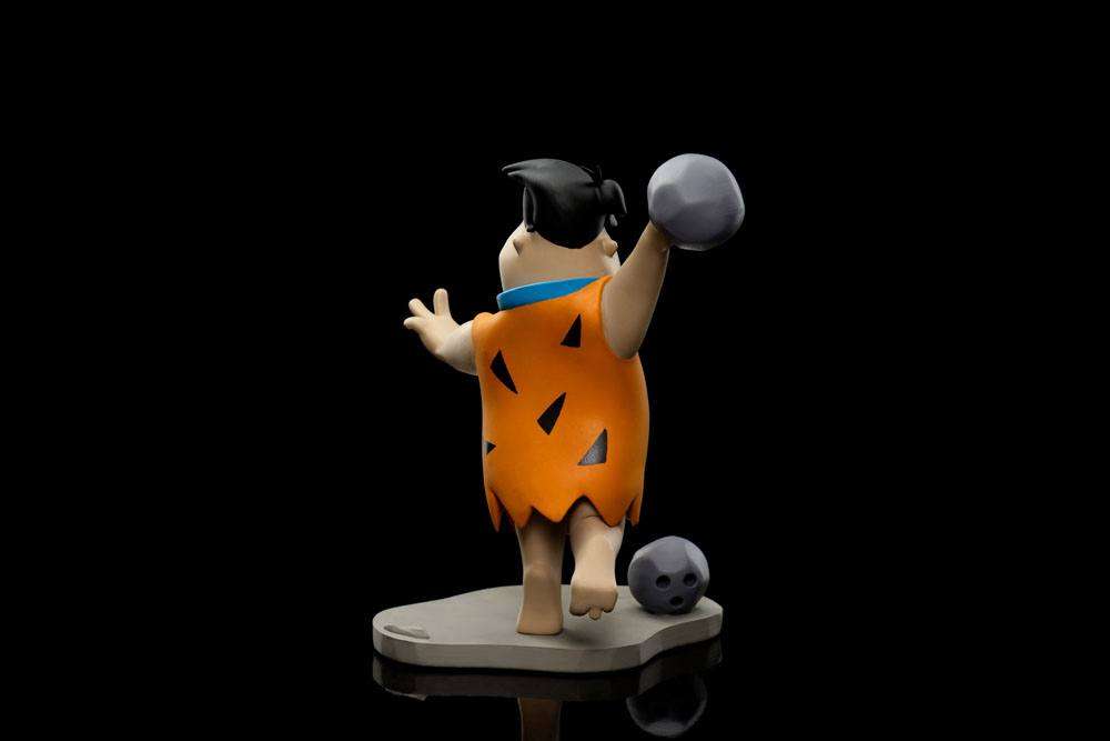 Side view of Iron Studios Fred Flintstone 17cm statue wearing his iconic orange tunic while bowling on a stone base.