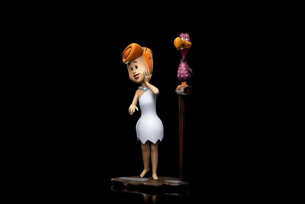 Iron Studios Wilma Flintstone 1/10 scale statue in a white dress standing next to a bird on a perch, side view.
