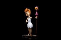 Iron Studios Wilma Flintstone 1/10 scale statue in a white dress standing next to a bird on a perch, side view.
