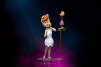 Iron Studios Wilma Flintstone 1/10 scale statue in a white dress standing next to a bird on a perch, front view.