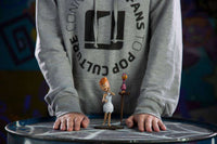 Iron Studios 1/10 Wilma Flintstone statue with a small bird figure, standing on a round table in front of a person.