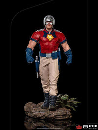 Front view of the 1/10 scale Iron Studios Peacemaker statue in his red and beige uniform with a chrome helmet.