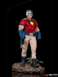 Iron Studios Peacemaker 1/10 scale statue featuring a metallic helmet, red and blue uniform, and tan pants on a base.