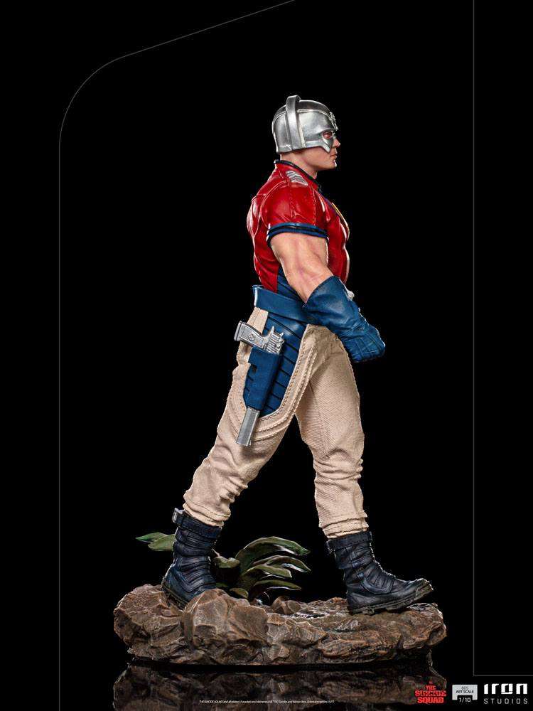 Side view of Iron Studios Peacemaker 1/10 scale statue wearing his iconic chrome helmet, red shirt, and tan pants.