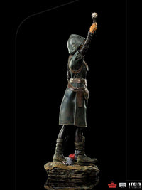 Side view of Iron Studios Ratcatcher II 1/10 scale statue wearing a dark hooded coat and holding a glowing device.