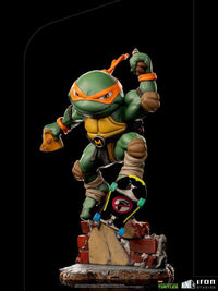 Iron Studios Michelangelo Mini Co. PVC figure on a skateboard, featuring a dynamic pose with pizza on a brick base.