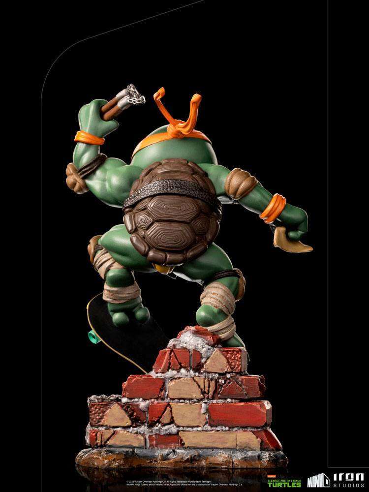 Back view of Iron Studios Michelangelo Mini Co. PVC figure on a brick base with nunchucks and a skateboard.