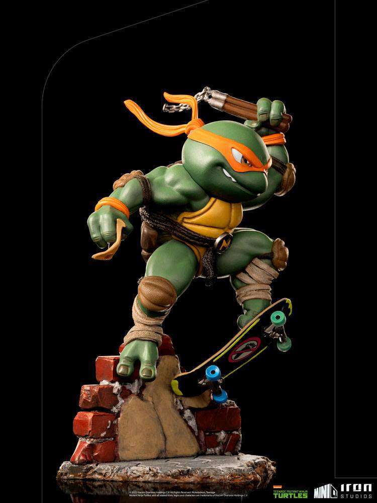 Iron Studios Michelangelo Mini Co. PVC figure in a dynamic pose with nunchucks and a skateboard on a brick base.
