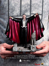 Front view of the 22 cm Iron Studios Dracula statue featuring a black cape with red lining and a wolf on a stone base.