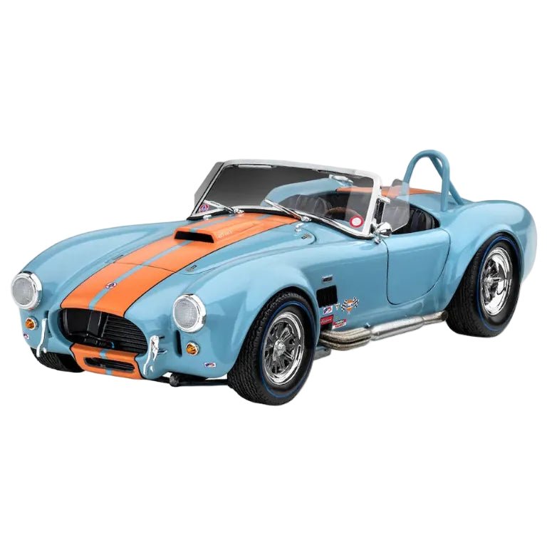 Revell '65 Shelby Cobra 427 model kit in light blue with orange racing stripes, shown from a front three-quarter angle.